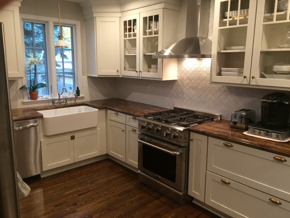 Inspiration for a large contemporary l-shaped medium tone wood floor and brown floor eat-in kitchen remodel in Minneapolis with a farmhouse sink, open cabinets, white cabinets, wood countertops, white backsplash, ceramic backsplash, stainless steel appliances and a peninsula