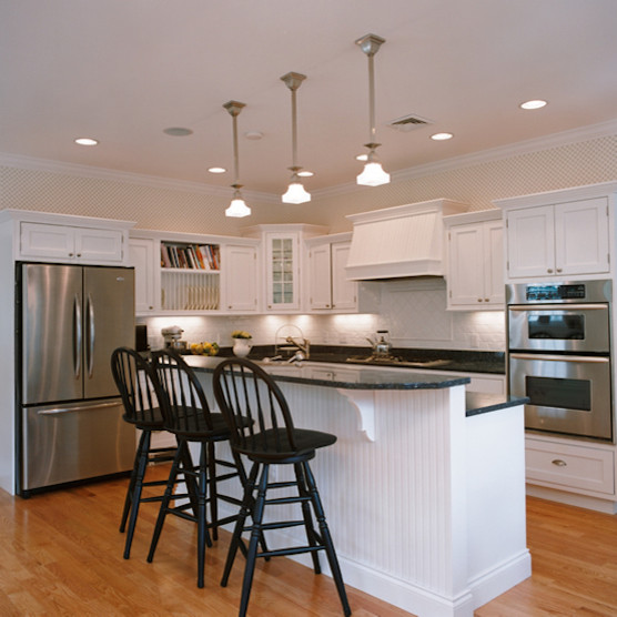 Exempel på ett stort klassiskt kök, med en nedsänkt diskho, luckor med upphöjd panel, vita skåp, bänkskiva i kalksten, vitt stänkskydd, rostfria vitvaror, mellanmörkt trägolv och en köksö