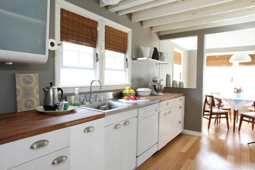 Idéer för att renovera ett mellanstort funkis brun brunt kök och matrum, med en integrerad diskho, släta luckor, vita skåp, träbänkskiva, vita vitvaror, ljust trägolv och beiget golv