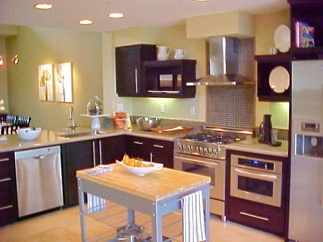 Inredning av ett modernt kök, med en undermonterad diskho, släta luckor, svarta skåp, granitbänkskiva, flerfärgad stänkskydd, stänkskydd i mosaik och rostfria vitvaror