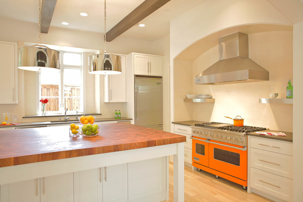 Inspiration for a contemporary l-shaped kitchen remodel in Dallas with white cabinets, wood countertops, colored appliances, shaker cabinets and beige backsplash