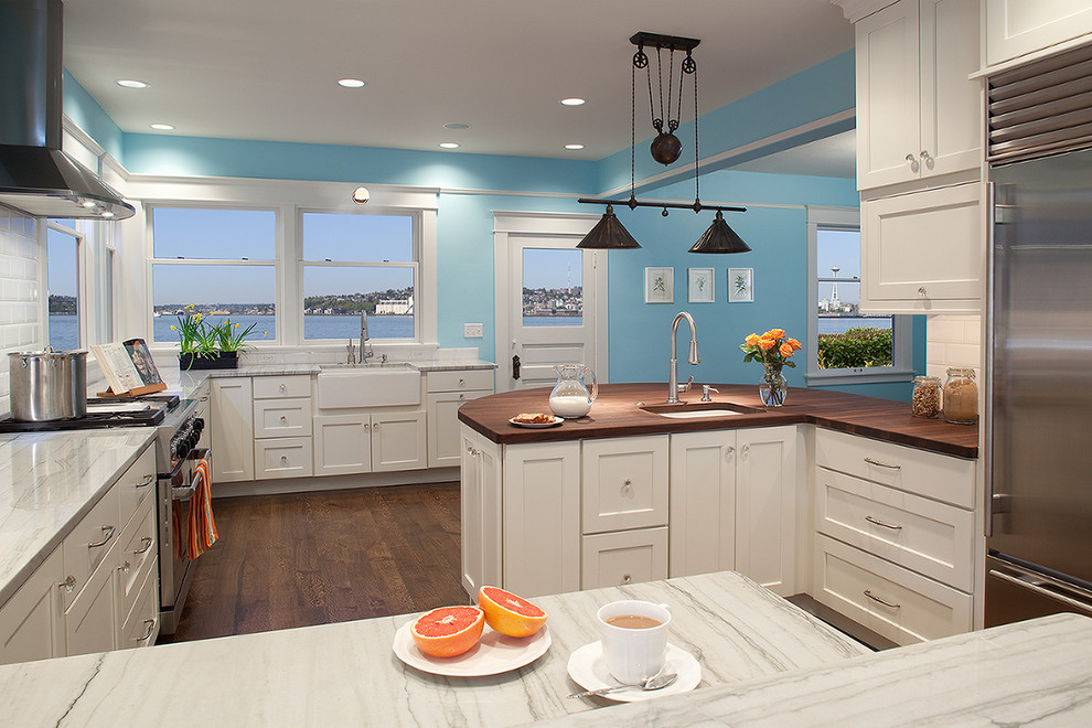 Inspiration for a mid-sized contemporary u-shaped dark wood floor and brown floor eat-in kitchen remodel in Seattle with a farmhouse sink, shaker cabinets, white cabinets, white backsplash, subway tile backsplash, stainless steel appliances, granite countertops and a peninsula