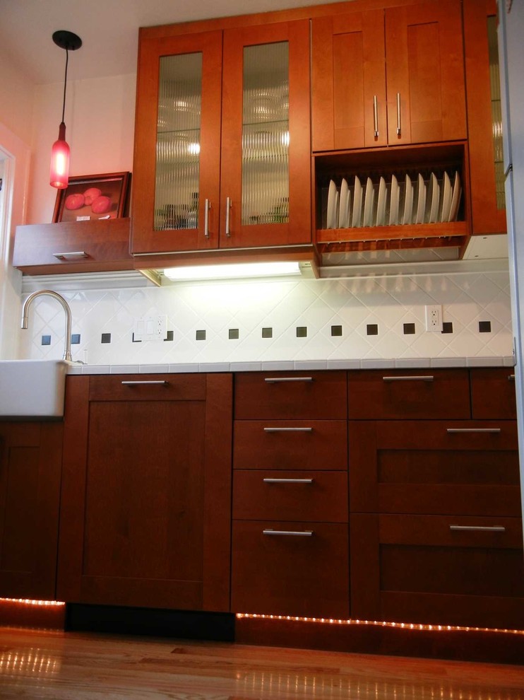 Exemple d'une arrière-cuisine linéaire en bois brun de taille moyenne avec un placard à porte vitrée, une crédence blanche, un électroménager en acier inoxydable et parquet clair.