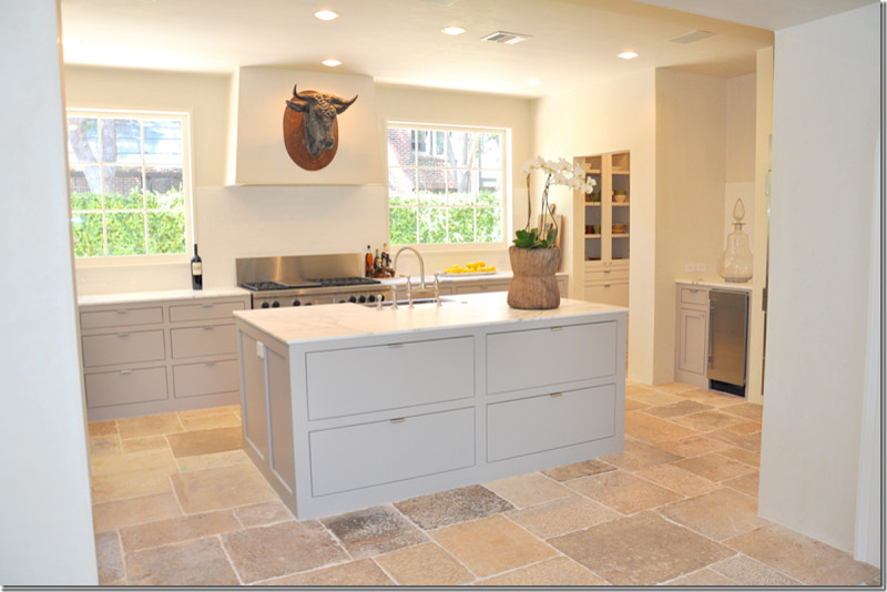 Example of a mid-sized tuscan u-shaped limestone floor kitchen pantry design in New York with a drop-in sink, flat-panel cabinets, beige cabinets, marble countertops, white backsplash, stone slab backsplash, colored appliances and an island