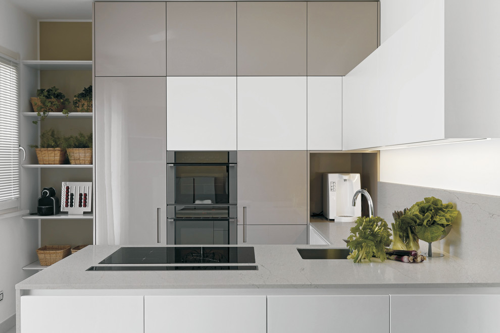 Cette photo montre une cuisine grise et blanche tendance avec un plan de travail en quartz modifié, un évier encastré, un placard à porte plane, des portes de placard grises, une crédence grise et une péninsule.