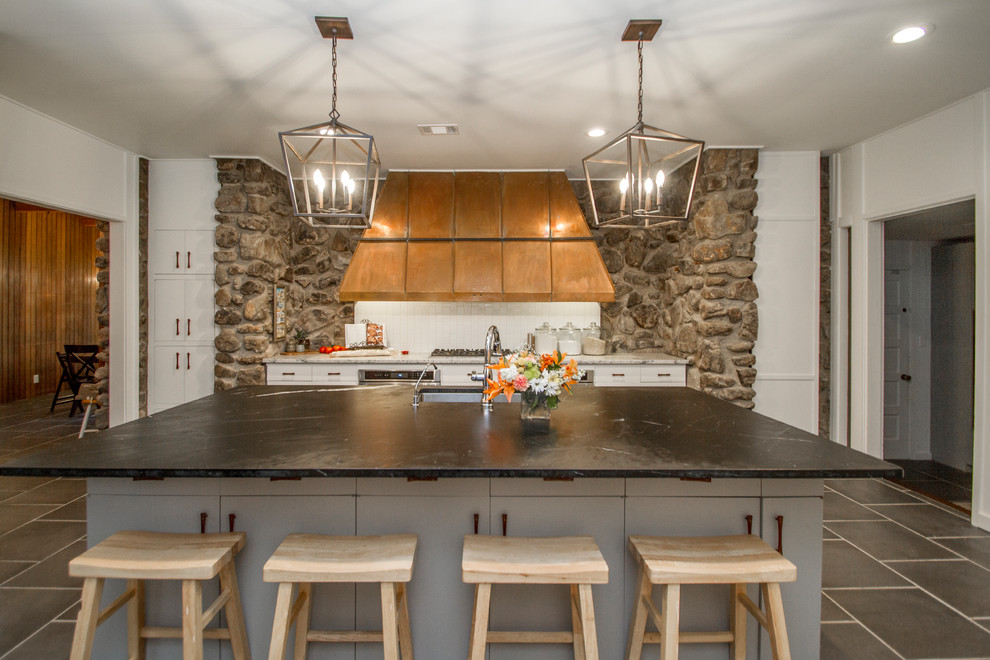 リトルロックにあるミッドセンチュリースタイルのおしゃれなアイランドキッチン (アンダーカウンターシンク、フラットパネル扉のキャビネット、白いキャビネット、白いキッチンパネル、グレーの床) の写真