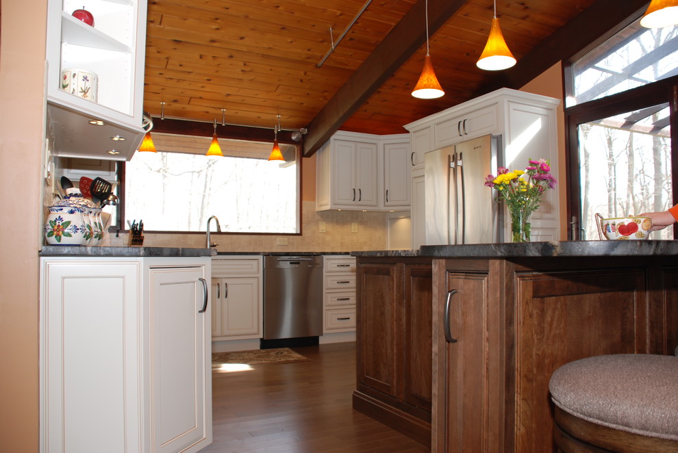Exempel på ett mellanstort rustikt kök, med en undermonterad diskho, vita skåp, granitbänkskiva, beige stänkskydd, stänkskydd i keramik, rostfria vitvaror, mellanmörkt trägolv, en köksö och luckor med infälld panel