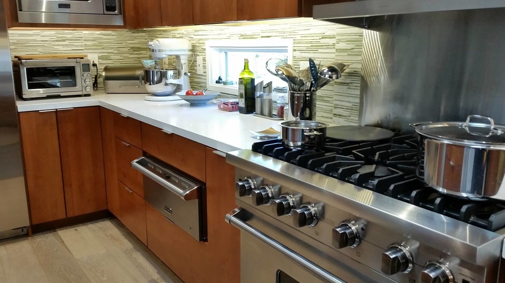 Example of a large trendy u-shaped light wood floor eat-in kitchen design in San Francisco with an undermount sink, flat-panel cabinets, medium tone wood cabinets, quartz countertops, green backsplash, glass tile backsplash, stainless steel appliances and an island
