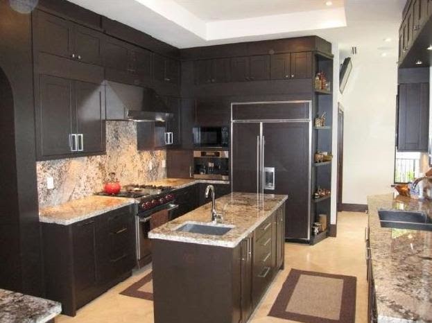 Bild på ett mellanstort funkis l-kök, med en undermonterad diskho, skåp i shakerstil, bruna skåp, granitbänkskiva, beige stänkskydd, stänkskydd i stenkakel, integrerade vitvaror, klinkergolv i porslin, en köksö och beiget golv