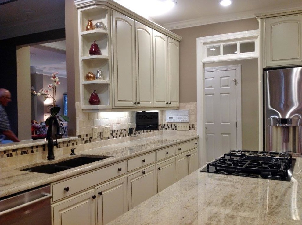 Lantlig inredning av ett mellanstort kök, med vita skåp, granitbänkskiva, flerfärgad stänkskydd, rostfria vitvaror, en köksö och luckor med upphöjd panel