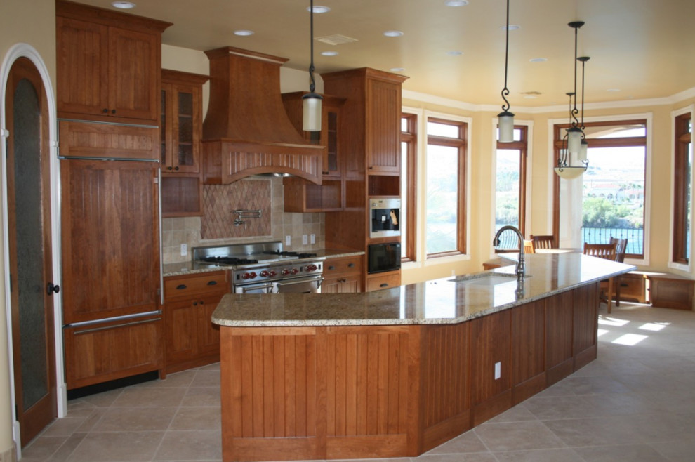 Inspiration for a mid-sized timeless single-wall travertine floor and beige floor eat-in kitchen remodel in Salt Lake City with an undermount sink, recessed-panel cabinets, dark wood cabinets, granite countertops, brown backsplash, stone tile backsplash, paneled appliances and an island