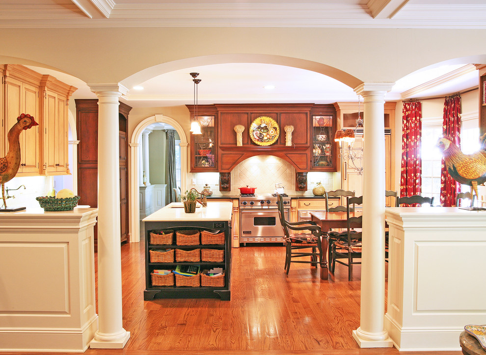 Пример оригинального дизайна: кухня в классическом стиле с обеденным столом, фасадами цвета дерева среднего тона и техникой из нержавеющей стали