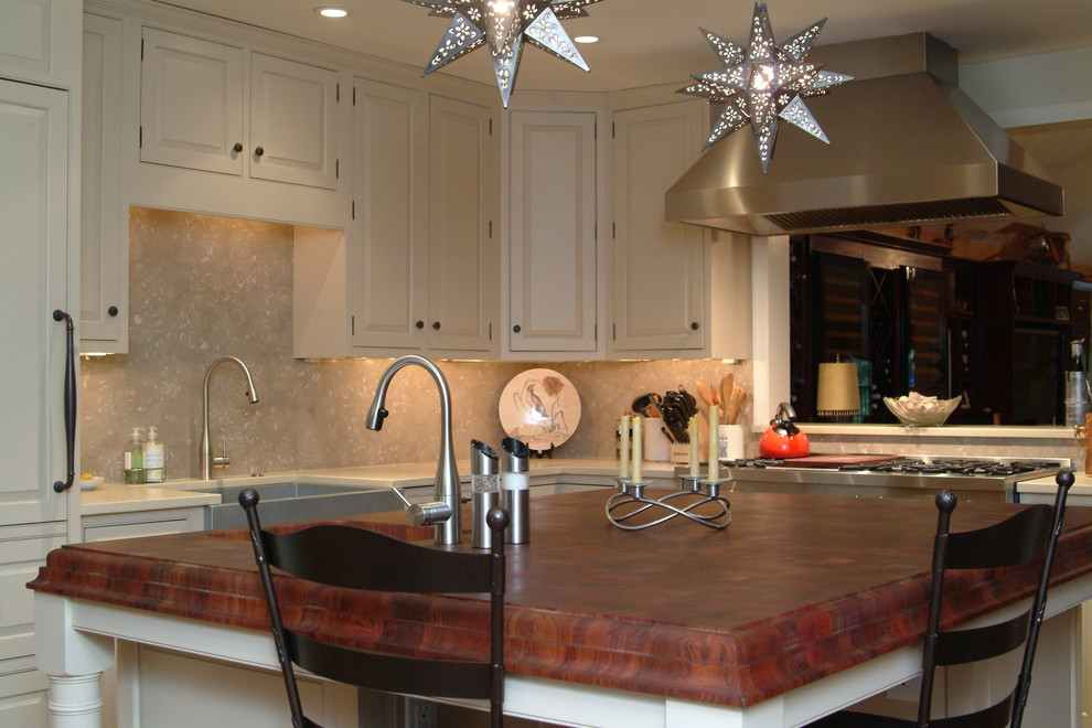 Bild på ett mellanstort funkis kök, med en rustik diskho, luckor med upphöjd panel, beige skåp, bänkskiva i kalksten, beige stänkskydd, stänkskydd i sten, rostfria vitvaror, mellanmörkt trägolv och en köksö