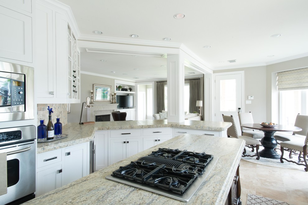 Example of a mid-sized transitional galley travertine floor eat-in kitchen design in Houston with an undermount sink, recessed-panel cabinets, white cabinets, granite countertops, brown backsplash, stone tile backsplash, stainless steel appliances and an island