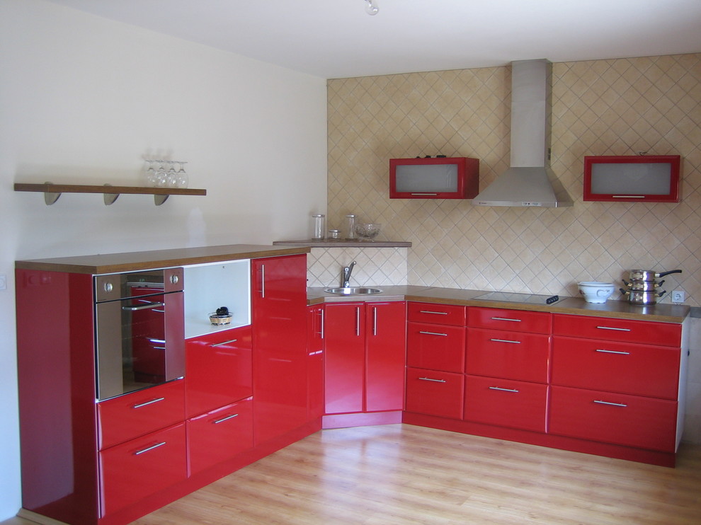 Источник вдохновения для домашнего уюта: кухня в стиле фьюжн с плоскими фасадами, техникой из нержавеющей стали, накладной мойкой, красными фасадами, бежевым фартуком и мойкой в углу