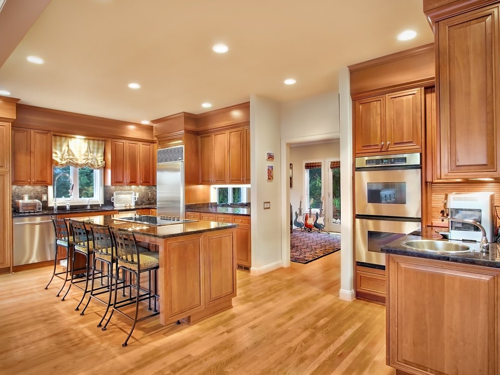 Klassische Küche mit Einbauwaschbecken, profilierten Schrankfronten, hellbraunen Holzschränken und Küchengeräten aus Edelstahl in Seattle