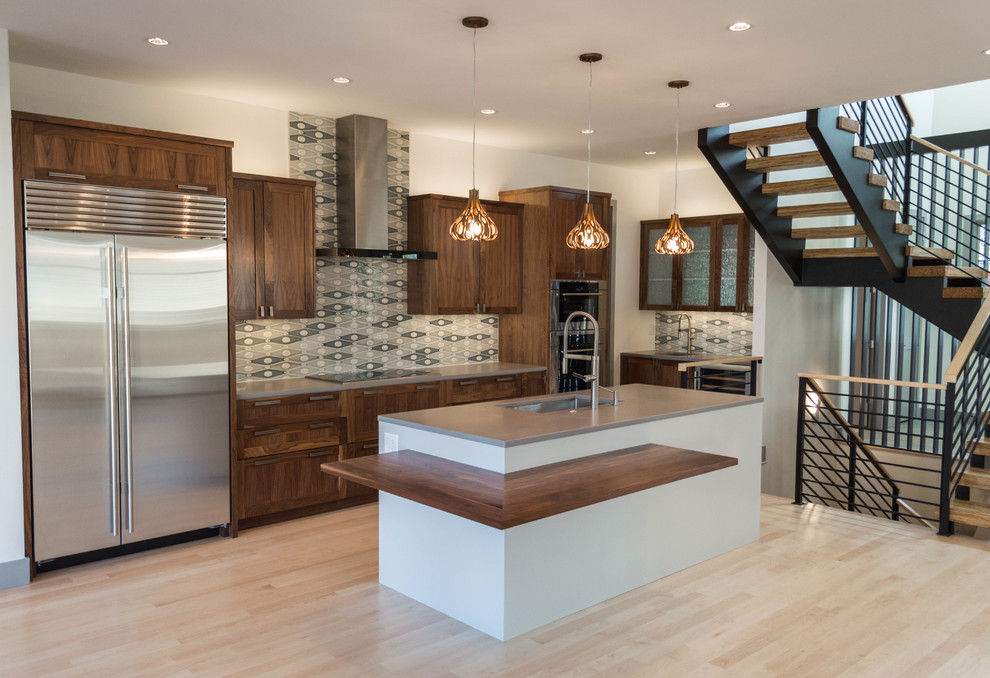 Inspiration for a mid-sized transitional l-shaped light wood floor eat-in kitchen remodel in Denver with shaker cabinets, dark wood cabinets, solid surface countertops, green backsplash, porcelain backsplash and an island