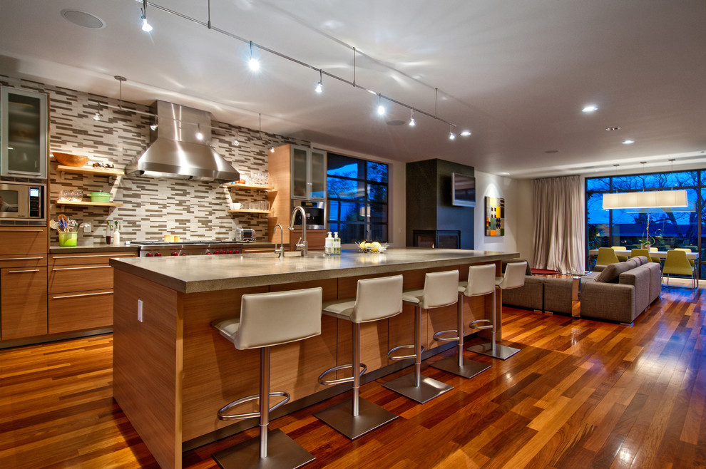 Bild på ett funkis kök med öppen planlösning, med släta luckor, skåp i mellenmörkt trä, bänkskiva i betong, flerfärgad stänkskydd, stänkskydd i stickkakel och rostfria vitvaror