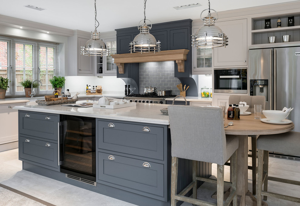 Photo of a medium sized classic l-shaped kitchen in Hampshire with grey cabinets, composite countertops, stainless steel appliances, ceramic flooring, an island, beige floors, shaker cabinets, grey splashback and metro tiled splashback.
