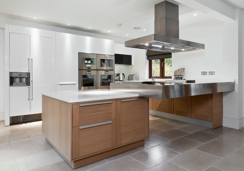 This is an example of a large contemporary kitchen in Hampshire with flat-panel cabinets, white cabinets, stainless steel worktops, beige floors and integrated appliances.