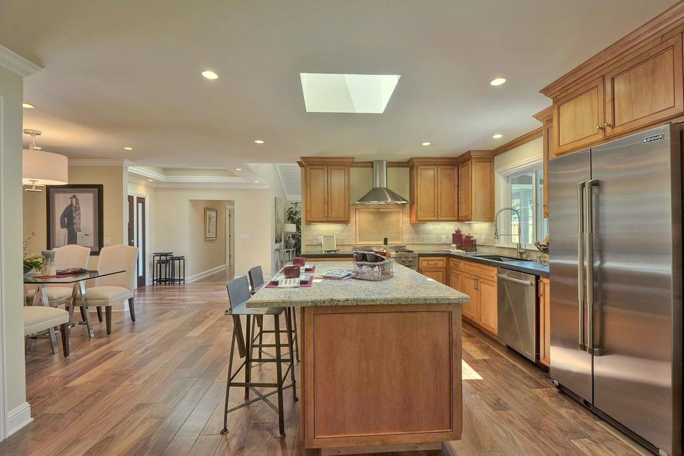 Inspiration for a timeless l-shaped light wood floor eat-in kitchen remodel in San Francisco with an undermount sink, recessed-panel cabinets, medium tone wood cabinets, granite countertops, beige backsplash, ceramic backsplash, stainless steel appliances and an island