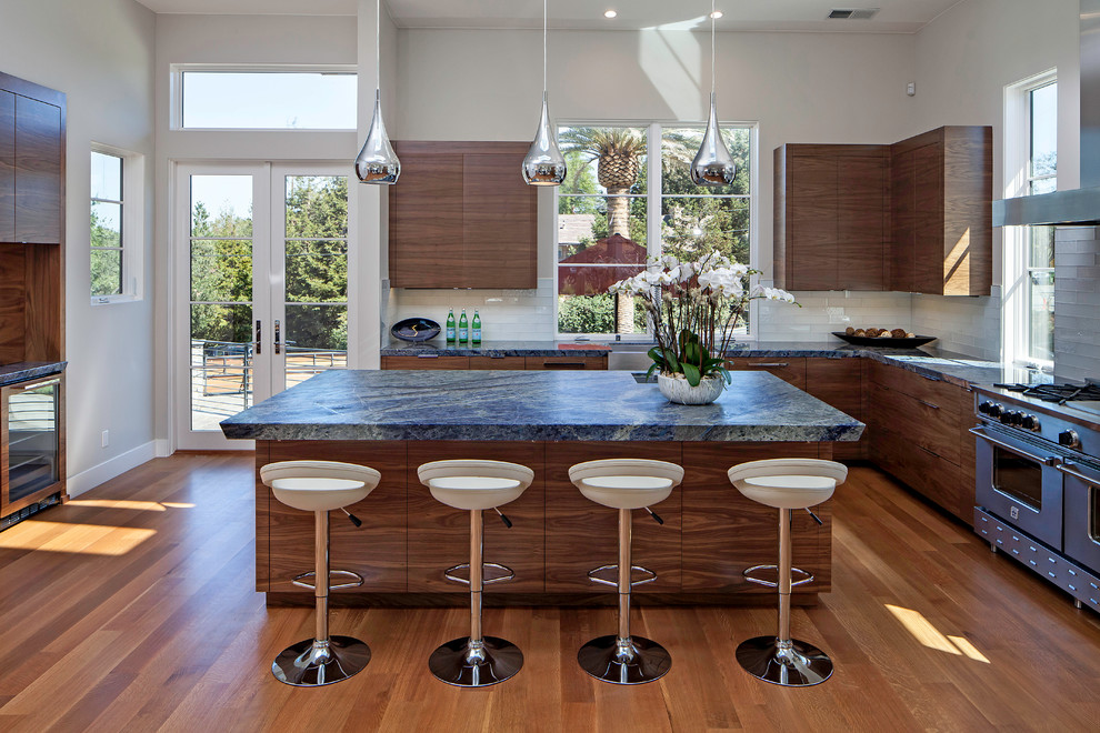 Inspiration for a contemporary l-shaped medium tone wood floor kitchen remodel in San Francisco with flat-panel cabinets, dark wood cabinets, white backsplash, glass tile backsplash, stainless steel appliances and an island