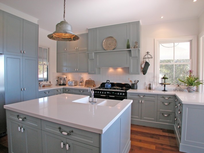 Inspiration for a classic u-shaped kitchen in Sydney with a belfast sink, blue cabinets, white splashback, stainless steel appliances, recessed-panel cabinets, medium hardwood flooring and an island.