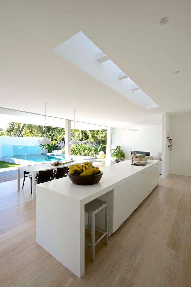 Zweizeilige Moderne Wohnküche mit flächenbündigen Schrankfronten, weißen Schränken, Quarzwerkstein-Arbeitsplatte und Kücheninsel in Sydney