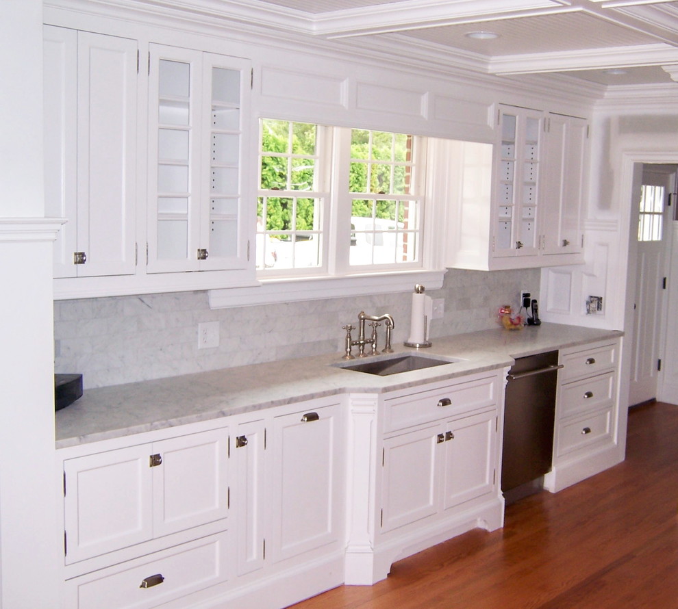 Inspiration for a transitional galley medium tone wood floor eat-in kitchen remodel in New York with an island, shaker cabinets, white cabinets, marble countertops, white backsplash, subway tile backsplash, stainless steel appliances and an undermount sink