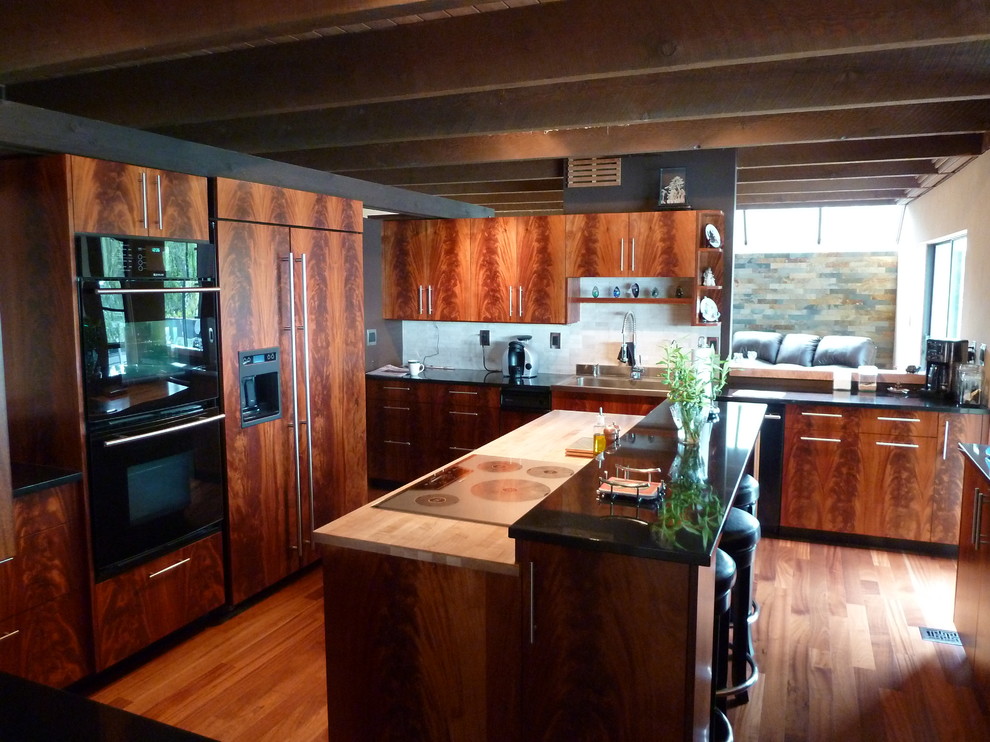 Modern inredning av ett mellanstort, avskilt kök, med en dubbel diskho, släta luckor, granitbänkskiva, vitt stänkskydd, stänkskydd i porslinskakel, svarta vitvaror, mellanmörkt trägolv och en köksö