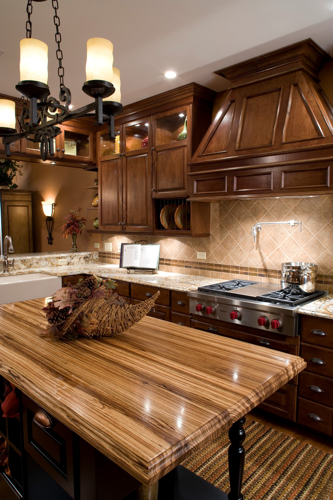 Inredning av ett klassiskt litet kök och matrum, med en rustik diskho, luckor med upphöjd panel, skåp i slitet trä, granitbänkskiva, beige stänkskydd, stänkskydd i keramik, rostfria vitvaror, mellanmörkt trägolv och en köksö