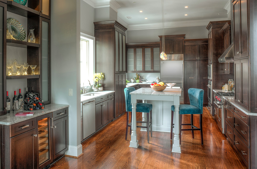 Example of a mid-sized trendy u-shaped medium tone wood floor and brown floor enclosed kitchen design in Charlotte with an undermount sink, shaker cabinets, dark wood cabinets, marble countertops, stainless steel appliances and an island