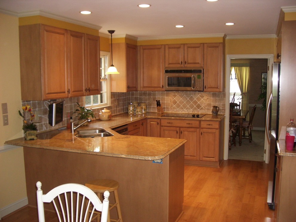 Exempel på ett mellanstort klassiskt kök, med en dubbel diskho, luckor med upphöjd panel, skåp i mellenmörkt trä, rostfria vitvaror, mellanmörkt trägolv och en halv köksö