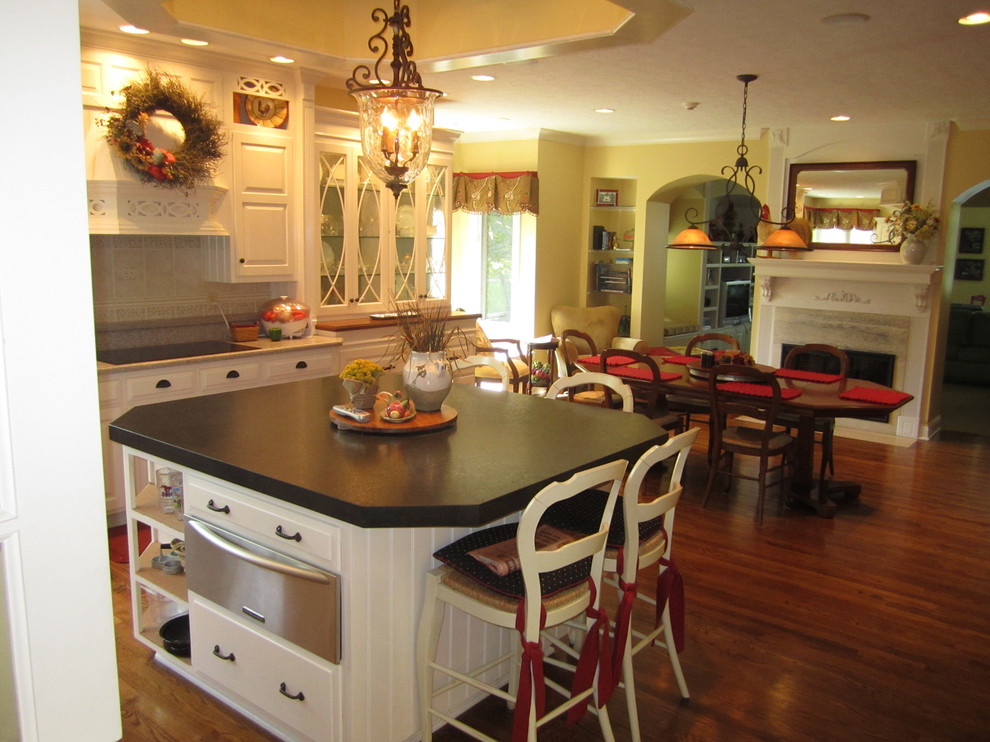 Eat-in kitchen - mid-sized farmhouse l-shaped medium tone wood floor and brown floor eat-in kitchen idea in Indianapolis with raised-panel cabinets, white cabinets, quartz countertops, gray backsplash, porcelain backsplash, paneled appliances, an island and gray countertops