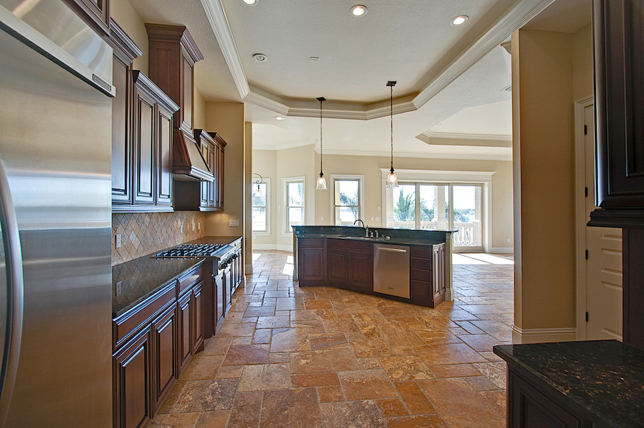 Example of a trendy galley ceramic tile kitchen design in Tampa with a drop-in sink, raised-panel cabinets, medium tone wood cabinets, granite countertops, beige backsplash and an island