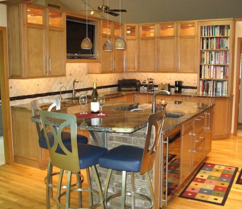 Foto på ett avskilt, mycket stort l-kök, med en undermonterad diskho, luckor med infälld panel, skåp i ljust trä, laminatbänkskiva, svart stänkskydd, rostfria vitvaror, ljust trägolv och en köksö