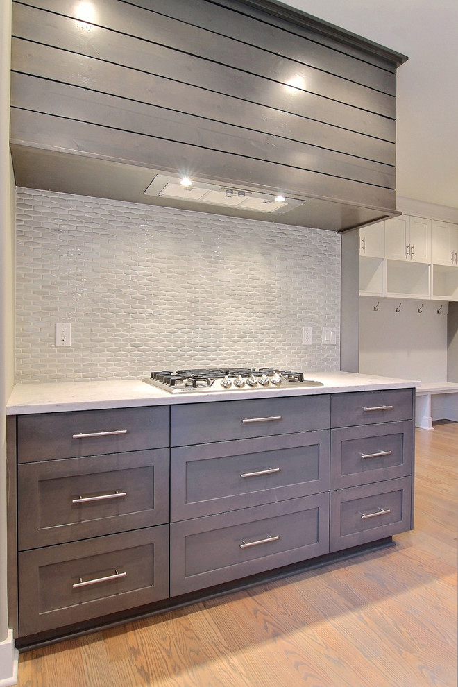 Example of a mid-sized minimalist u-shaped light wood floor eat-in kitchen design in Chicago with an undermount sink, shaker cabinets, gray cabinets, quartzite countertops, gray backsplash, mosaic tile backsplash, stainless steel appliances and an island