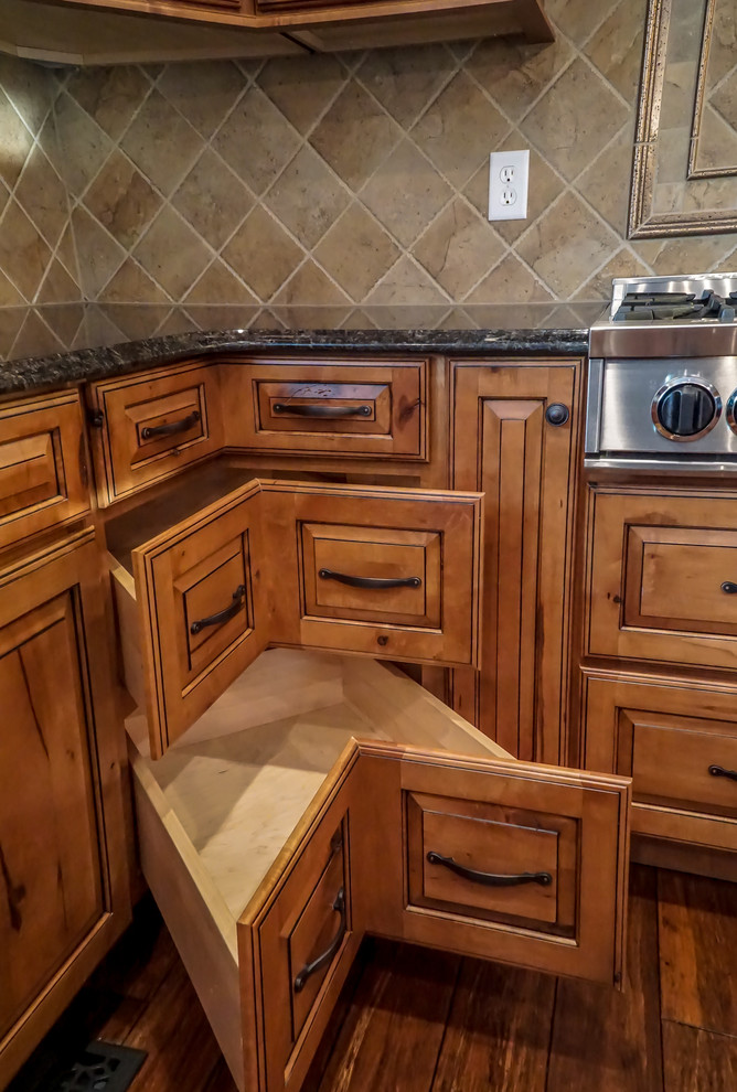 Mid-sized mountain style u-shaped medium tone wood floor eat-in kitchen photo in Chicago with an undermount sink, raised-panel cabinets, granite countertops, beige backsplash, stone tile backsplash, stainless steel appliances and an island