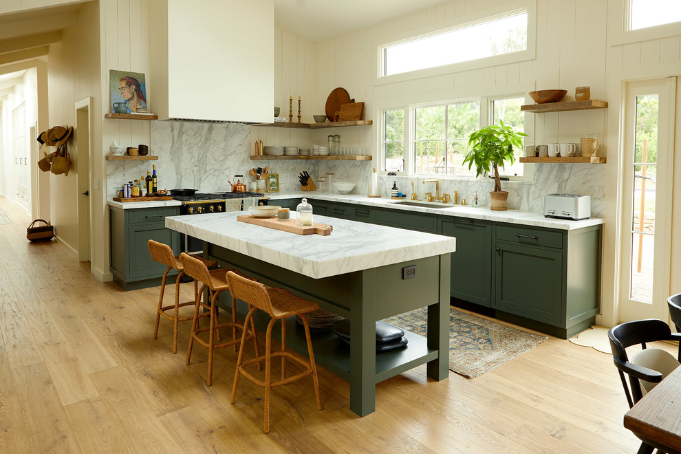 Inspiration for a country l-shaped kitchen/diner in Santa Barbara with a submerged sink, shaker cabinets, green cabinets, white splashback, stone slab splashback, black appliances, medium hardwood flooring, an island and brown floors.