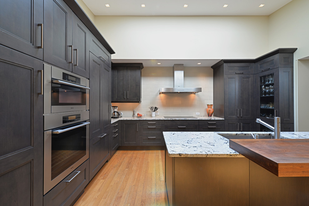 Eat-in kitchen - large modern l-shaped light wood floor and beige floor eat-in kitchen idea in Philadelphia with an undermount sink, recessed-panel cabinets, gray cabinets, granite countertops, white backsplash, ceramic backsplash, stainless steel appliances and an island