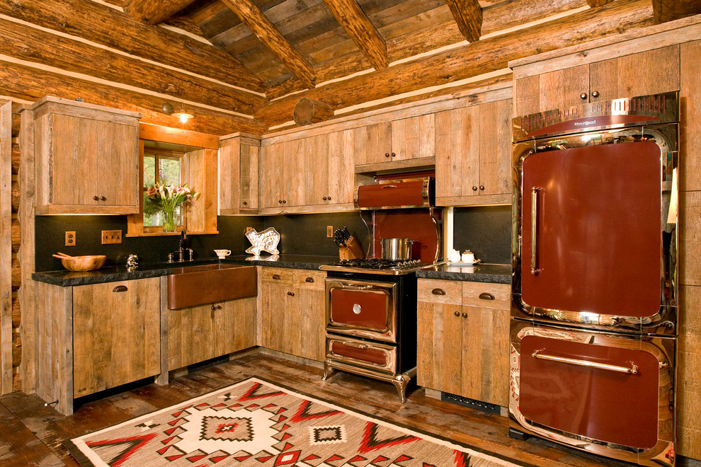 Photo of a rustic l-shaped kitchen in Philadelphia with a belfast sink, flat-panel cabinets, light wood cabinets, black splashback, coloured appliances and stone slab splashback.