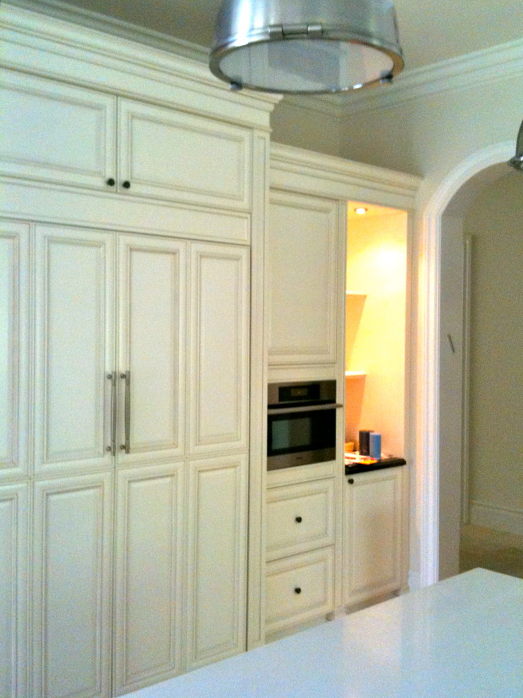 Inredning av ett klassiskt stort kök, med en enkel diskho, luckor med upphöjd panel, vita skåp, bänkskiva i kvartsit, flerfärgad stänkskydd, stänkskydd i stenkakel, rostfria vitvaror, klinkergolv i keramik, en köksö och beiget golv
