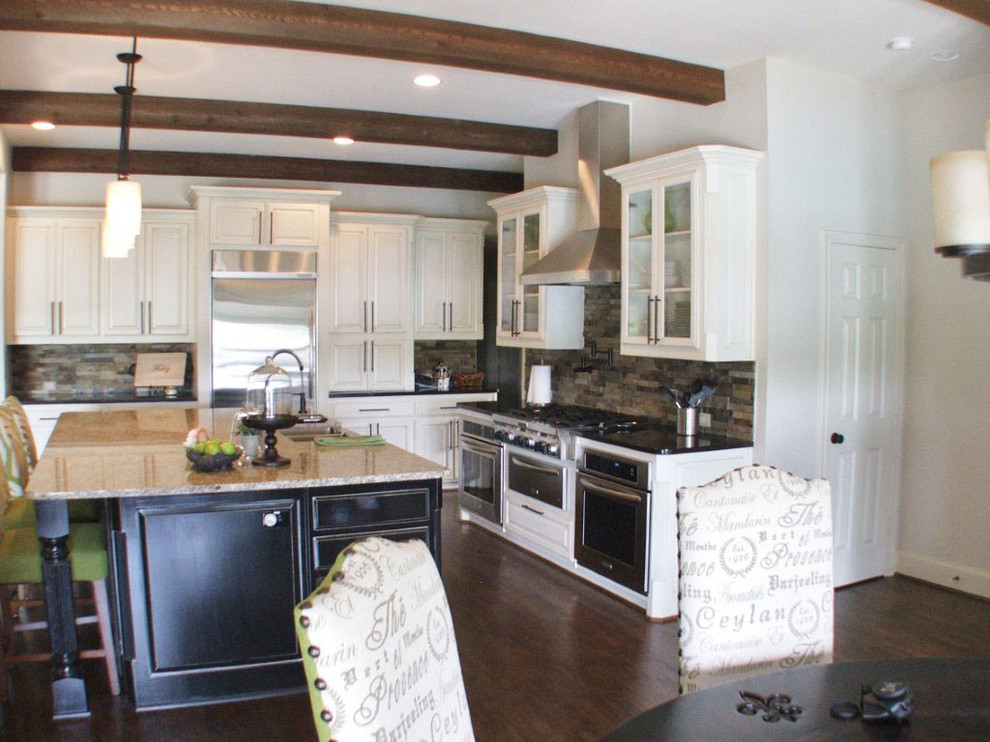 Example of a mid-sized transitional l-shaped dark wood floor eat-in kitchen design in Dallas with white cabinets, white backsplash, stainless steel appliances, an island, a farmhouse sink, raised-panel cabinets, granite countertops and stone tile backsplash