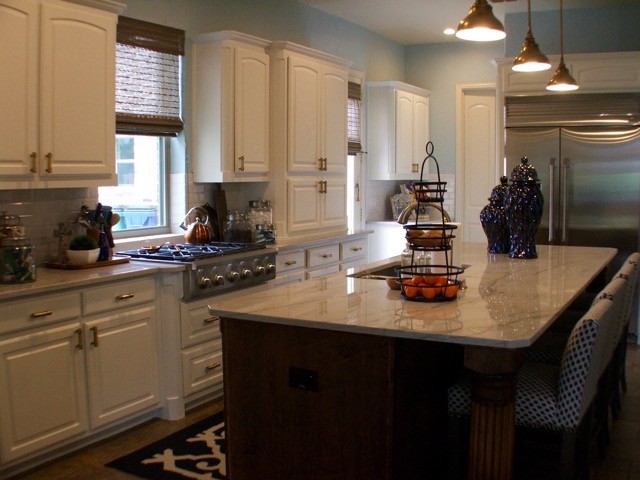 This is an example of a large classic l-shaped kitchen/diner in Dallas with a submerged sink, raised-panel cabinets, white cabinets, composite countertops, white splashback, metro tiled splashback, stainless steel appliances, ceramic flooring and an island.
