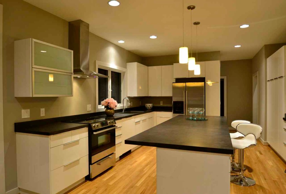 Example of a mid-sized minimalist l-shaped light wood floor eat-in kitchen design in Cincinnati with an undermount sink, glass-front cabinets, white cabinets, laminate countertops, stainless steel appliances and an island