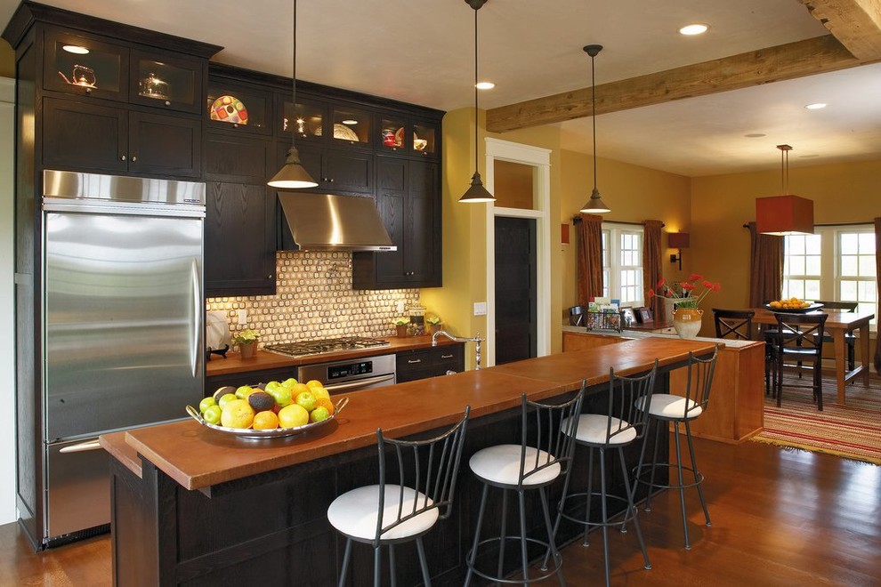 Exemple d'une grande cuisine américaine linéaire chic en bois foncé avec un placard à porte shaker, un plan de travail en cuivre, une crédence beige, une crédence en carreau de verre, un électroménager en acier inoxydable, un sol en bois brun et un sol marron.