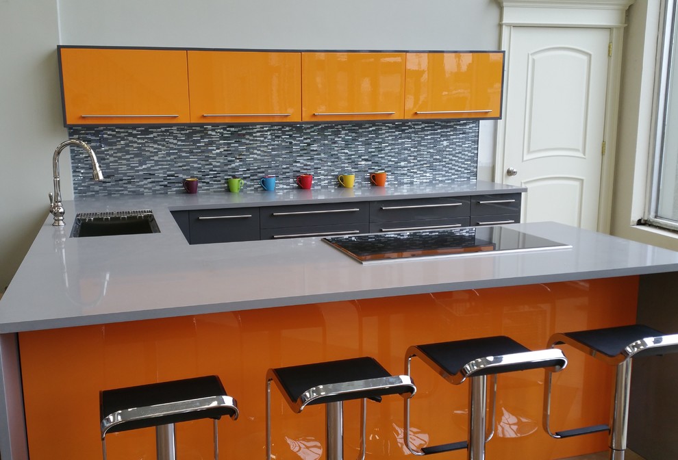 Esempio di una cucina ad U moderna chiusa e di medie dimensioni con ante lisce, ante arancioni, top in quarzo composito, paraspruzzi grigio, paraspruzzi con piastrelle di vetro, pavimento con piastrelle in ceramica, penisola e lavello sottopiano