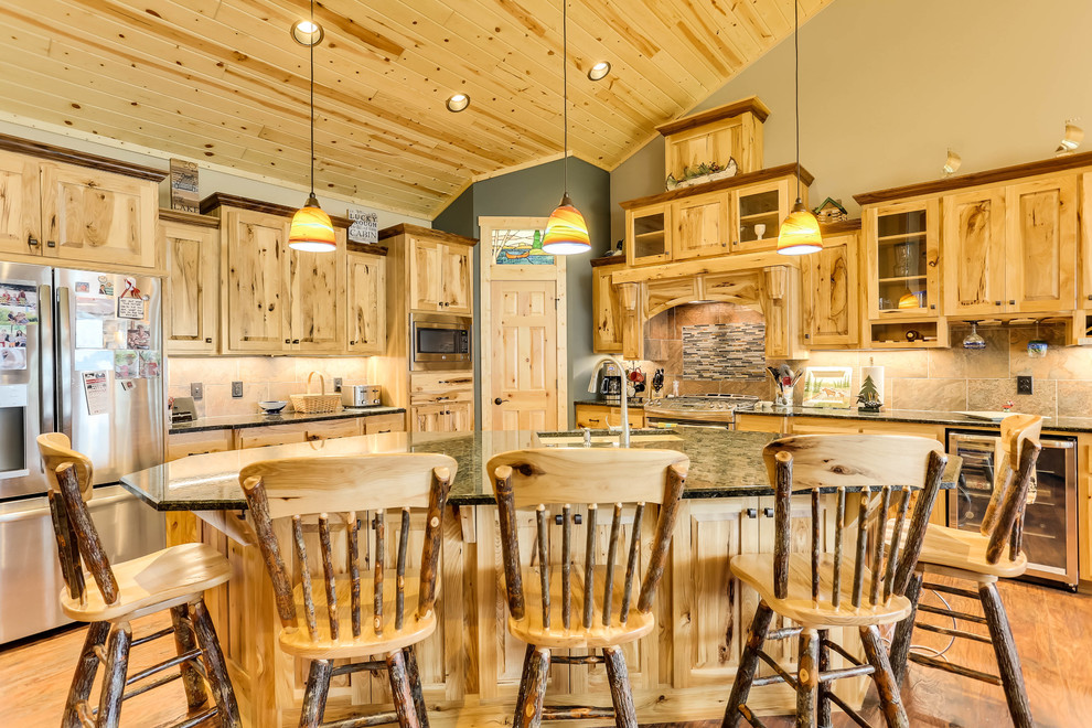 Rustic l-shaped kitchen in Minneapolis with a submerged sink, raised-panel cabinets, medium wood cabinets, brown splashback, stainless steel appliances, medium hardwood flooring, an island, brown floors and black worktops.