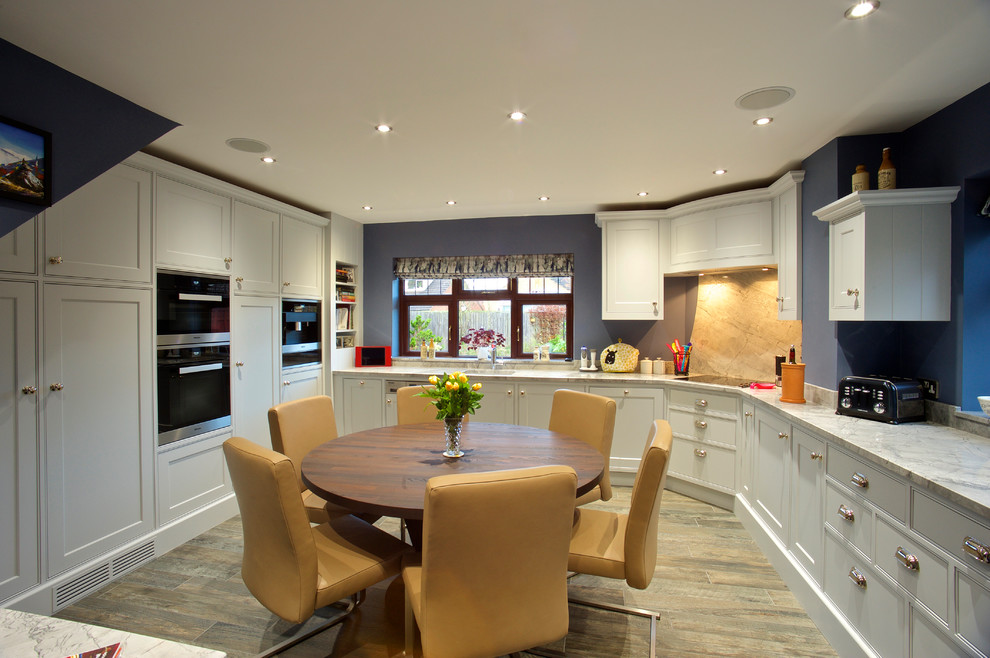 Traditional l-shaped kitchen/diner in Other with shaker cabinets, white cabinets, white splashback, black appliances, light hardwood flooring, an island and beige floors.