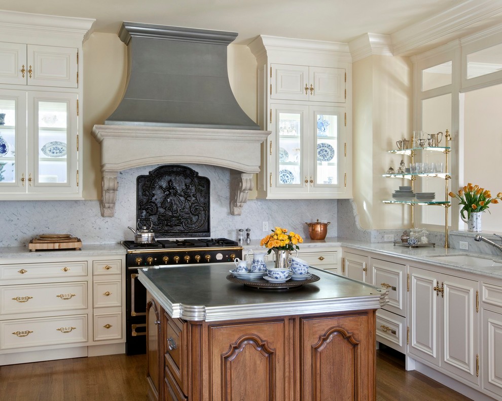Foto på ett mellanstort vintage kök, med luckor med upphöjd panel, vita skåp, svarta vitvaror, en undermonterad diskho, granitbänkskiva, grått stänkskydd, stänkskydd i sten, mellanmörkt trägolv och en köksö